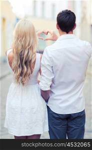 summer holidays, love, travel, tourism, relationship and dating concept - romantic couple in the city making heart shape