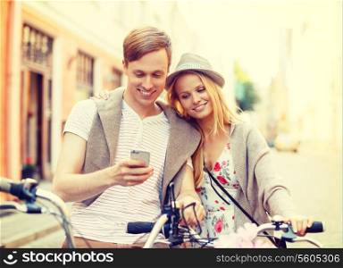 summer holidays, navigation, gps and dating concept - couple with bicycles and smartphone in the city