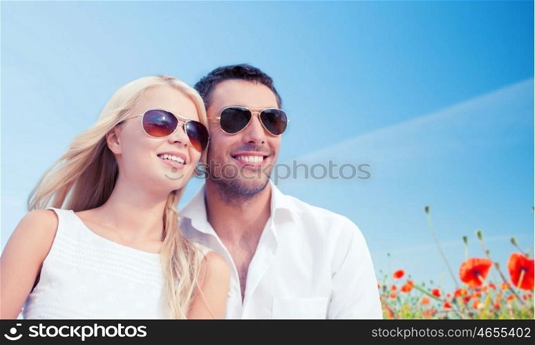 summer holidays, people and dating concept - happy couple in shades over blue sky and poppy field background