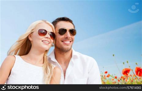 summer holidays, people and dating concept - happy couple in shades over blue sky and poppy field background