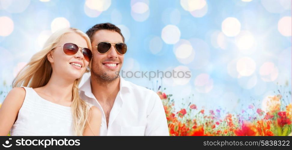 summer holidays, people and dating concept - happy couple in shades over blue lights and poppy field background