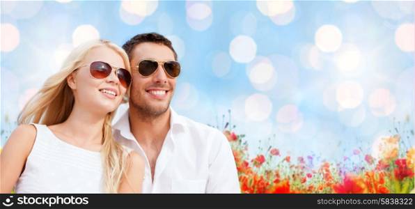 summer holidays, people and dating concept - happy couple in shades over blue lights and poppy field background