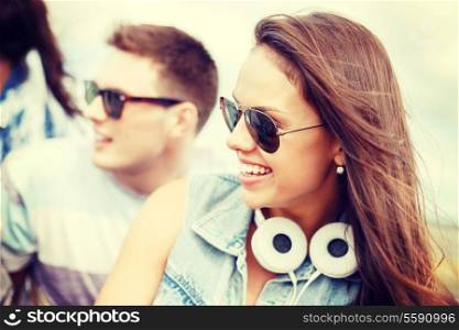 summer holidays, people and happiness concept - smiling teenage girl in sunglasses outdoors with friends