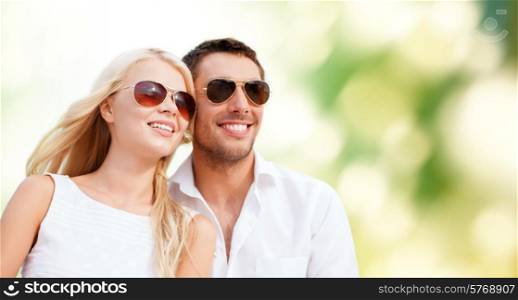 summer holidays, people, ecology and dating concept - happy couple in shades over green background