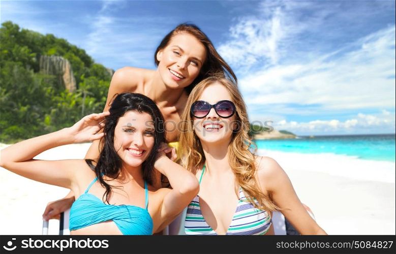 summer holidays, people, leisure, vacation and travel concept - happy smiling women sunbathing on chairs over exotic tropical beach background. happy women sunbathing on chairs at summer beach. happy women sunbathing on chairs at summer beach