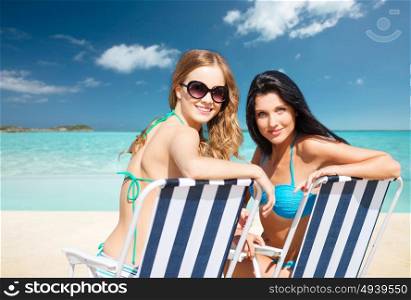 summer holidays, people, leisure, vacation and travel concept - happy women sunbathing in chairs over exotic tropical beach background. happy women sunbathing in chairs on summer beach