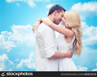 summer holidays, people, love and dating concept - happy couple hugging over blue sky and white clouds background