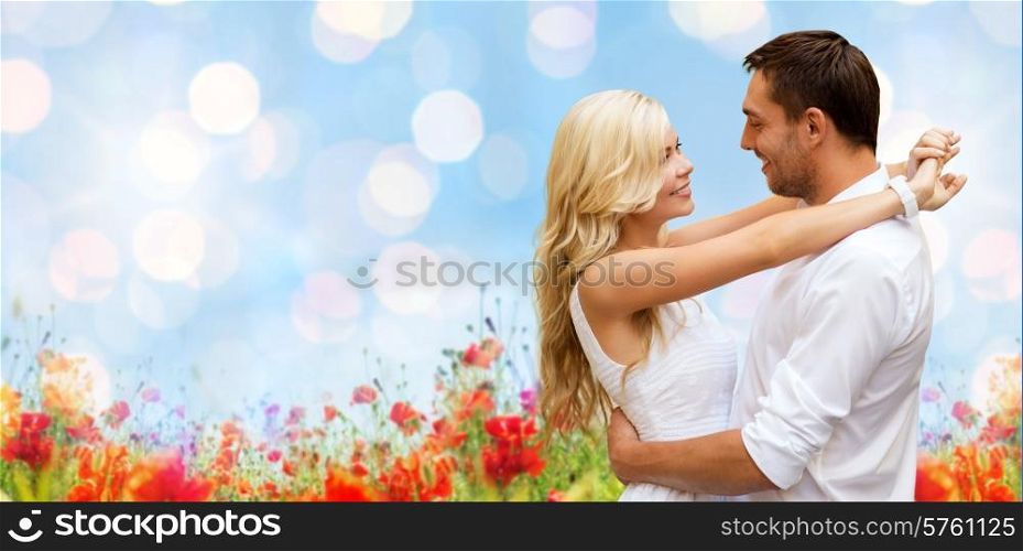 summer holidays, people, love and dating concept - happy couple hugging over blue sky lights and poppy field background