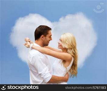 summer holidays, people, love and dating concept - happy couple hugging over heart shaped cloud and blue sky background