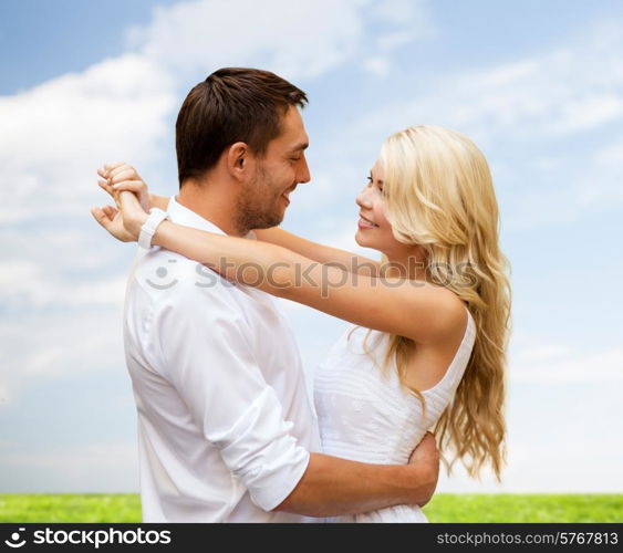 summer holidays, people, love and dating concept - happy couple hugging over blue sky and grass background