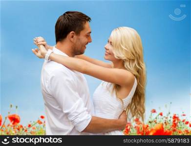 summer holidays, people, love and dating concept - happy couple hugging over blue sky and poppy field background