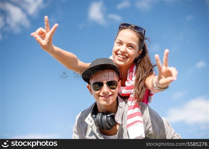 summer holidays, relationships and teenage concept - smiling teenagers in sunglasses having fun outside and showing v-sign