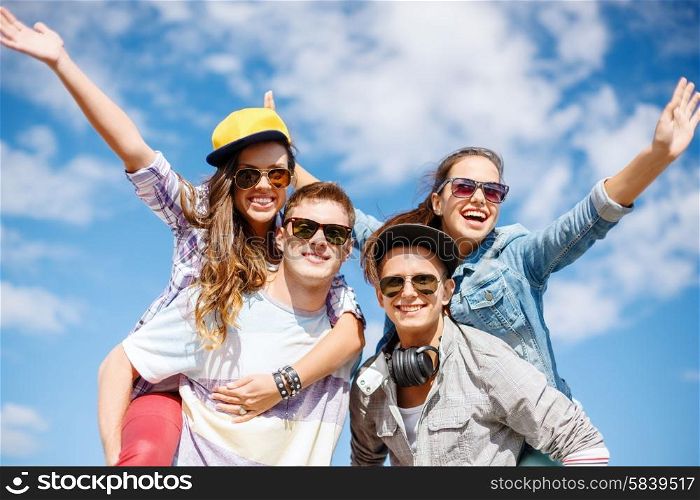 summer holidays, relationships and teenage concept - smiling teenagers in sunglasses having fun outside