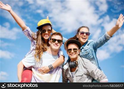 summer holidays, relationships and teenage concept - smiling teenagers in sunglasses having fun outside