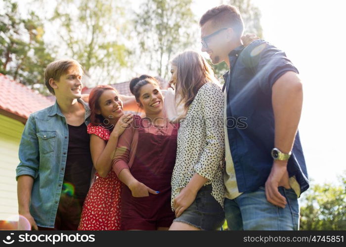 summer holidays, reunion, people and friendship concept - happy teenage friends hugging and talking at garden party