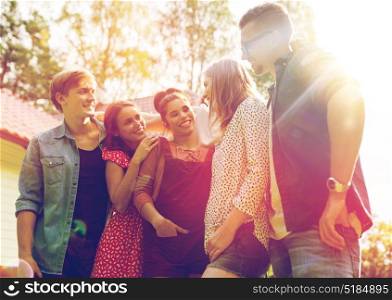 summer holidays, reunion, people and friendship concept - happy teenage friends hugging and talking at garden party. happy teenage friends hugging at summer garden