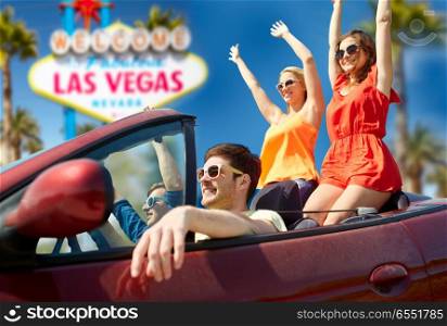 summer holidays, road trip and travel concept - happy friends driving in convertible car and waving hands over welcome to fabulous las vegas sign background. friends driving in convertible car at las vegas. friends driving in convertible car at las vegas