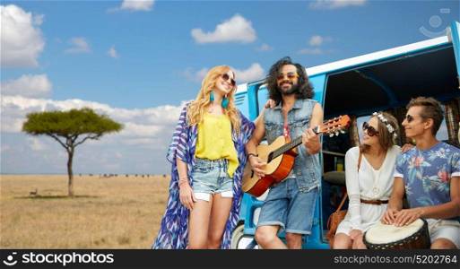 summer holidays, road trip, travel and people concept - happy young hippie friends with guitar and drum playing music at minivan car over african savannah background. hippie friends playing music at minivan in africa