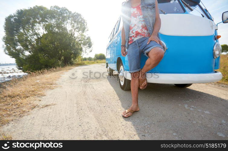 summer holidays, road trip, travel and people concept - hippie man at minivan car. hippie man at minivan car on road