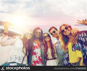 summer holidays, road trip, travel and people concept - smiling young hippie friends at minivan car showing peace hand sign over sea background. hippie friends at minivan car showing peace sign