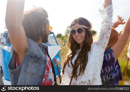 summer holidays, road trip, travel and people concept - smiling young hippie friends having fun and dancing near minivan car at seaside. smiling hippie friends having fun near minivan car
