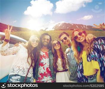 summer holidays, road trip, travel and people concept - smiling young hippie friends at minivan car showing peace hand sign over alps mountains background. hippie friends over minivan car showing peace sign