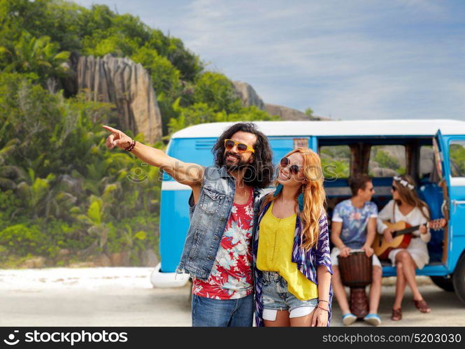 summer holidays, road trip, travel and people concept - smiling young hippie couple with friends in minivan car over exotic island beach background. happy hippie couples and minivan on island