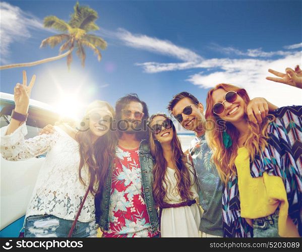 summer holidays, road trip, travel and people concept - smiling young hippie friends at minivan car showing peace hand sign over beach background. hippie friends at minivan car showing peace sign