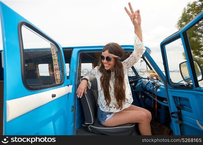 summer holidays, road trip, travel and people concept - smiling young hippie woman showing peace gesture in minivan car. happy hippie woman showing peace in minivan car