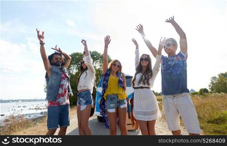 summer holidays, road trip, travel and people concept - smiling young hippie friends having fun and dancing near minivan car at seaside. smiling hippie friends having fun near minivan car