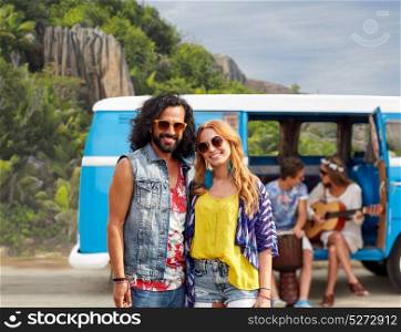 summer holidays, road trip, travel and people concept - smiling young hippie couple with friends in minivan car over exotic island background. happy hippie couples and minivan on island