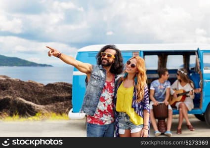 summer holidays, road trip, travel and people concept - smiling young hippie couple with friends in minivan car over island and sea background. happy hippie couples and minivan on island
