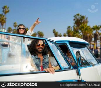 summer holidays, road trip, travel and vacation concept - smiling young hippie friends in minivan car on beach over venice beach in los angeles background. hippie friends in minivan car at venice beach