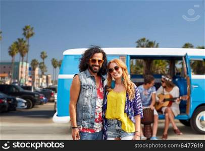 summer holidays, road trip, travel and vacation concept - smiling young hippie couple with friends over minivan car and venice beach in los angeles background. hippie couple over minivan at venice beach in la. hippie couple over minivan at venice beach in la