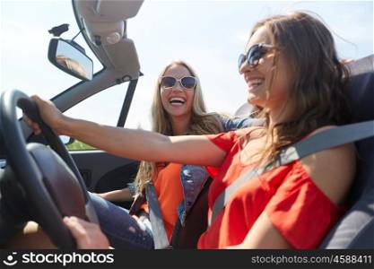 summer holidays, road trip, vacation, travel and people concept - happy young women driving in in cabriolet car and laughing. happy young women driving in cabriolet car