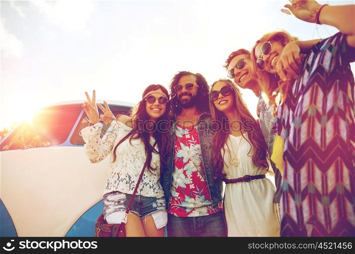 summer holidays, road trip, vacation, travel and people concept - smiling young hippie friends over minivan car showing peace hand sign