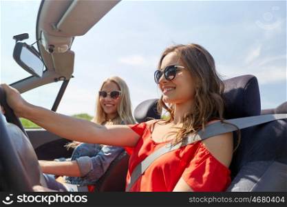 summer holidays, road trip, vacation, travel and people concept - smiling young women driving in in cabriolet car