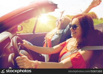summer holidays, road trip, vacation, travel and people concept - smiling young women driving in in cabriolet car. smiling young women driving in cabriolet car