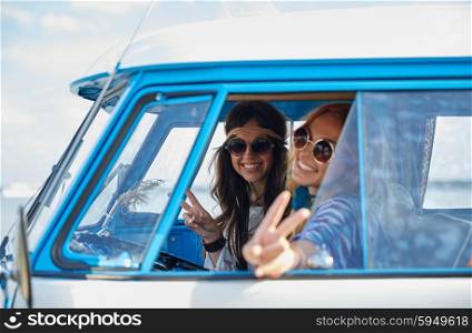 summer holidays, road trip, vacation, travel and people concept - smiling young hippie women driving minivan car and showing peace gesture
