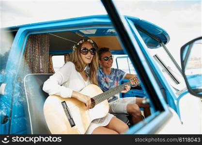 summer holidays, road trip, vacation, travel and people concept - smiling young hippie couple with guitar playing music in minivan car