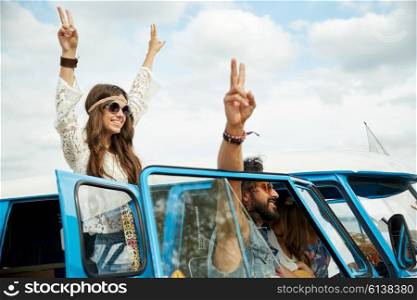 summer holidays, road trip, vacation, travel and people concept - smiling young hippie friends over minivan car showing peace hand sign