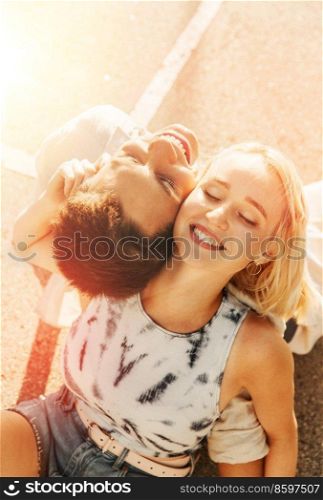 summer holidays, romantic and people concept - happy young couple sitting back to back on basketball playground. happy couple sitting on basketball playground