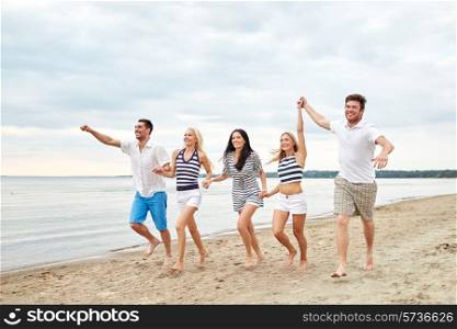 summer, holidays, sea, tourism and people concept - group of smiling friends in sunglasses running on beach