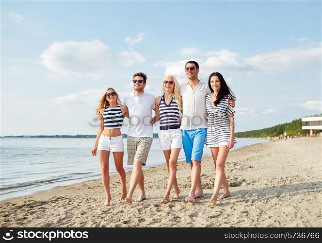 summer, holidays, sea, tourism and people concept - group of smiling friends in sunglasses walking on beach