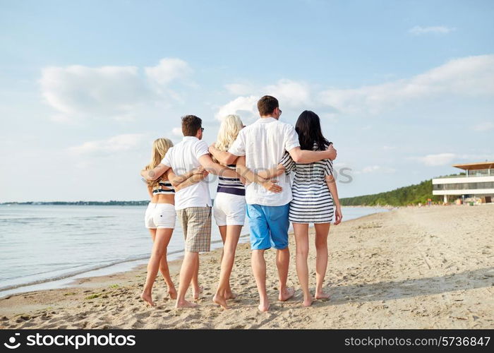 summer, holidays, sea, tourism and people concept - group of smiling friends hugging and walking on beach from back