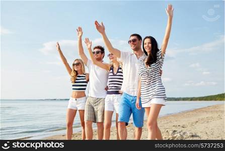 summer, holidays, sea, tourism and people concept - group of smiling friends in sunglasses walking on beach and waving hands