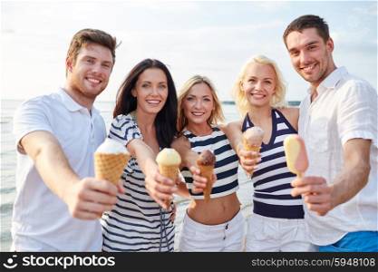 summer, holidays, sea, tourism and people concept - group of smiling friends showing ice cream on beach