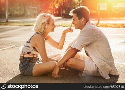 summer holidays, technology and people concept - happy couple with earphones listening to music on basketball playground. happy couple with earphones listening to music