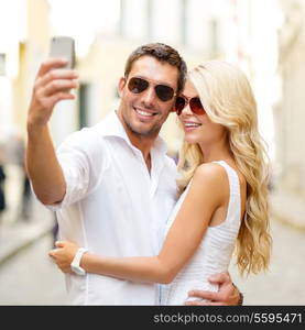 summer holidays, technology, love, relationship and dating concept - smiling couple taking selfie with smartphone in the city