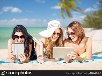 summer holidays, technology, people, travel and internet concept - happy young women in bikinis with tablet pc computers sunbathing over exotic tropical beach with palm trees and sea shore background